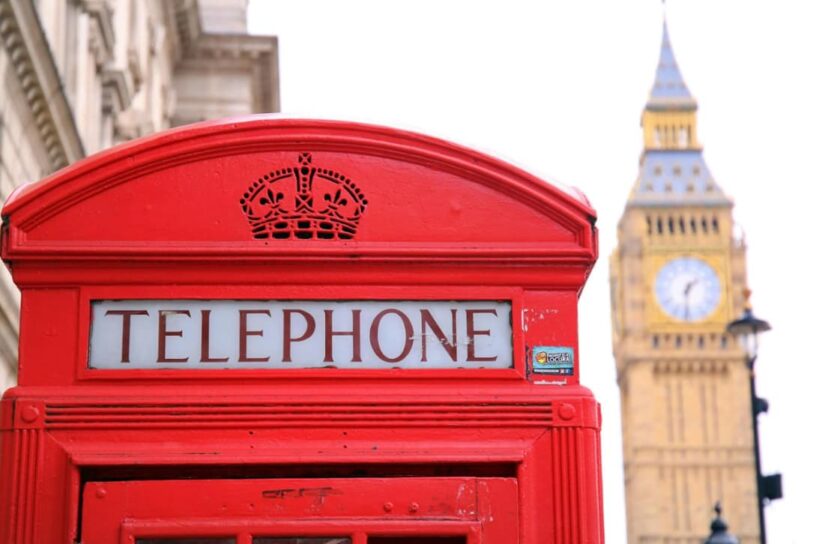 A traditional red British telephone box, in front of the Big Ben clock tower in London