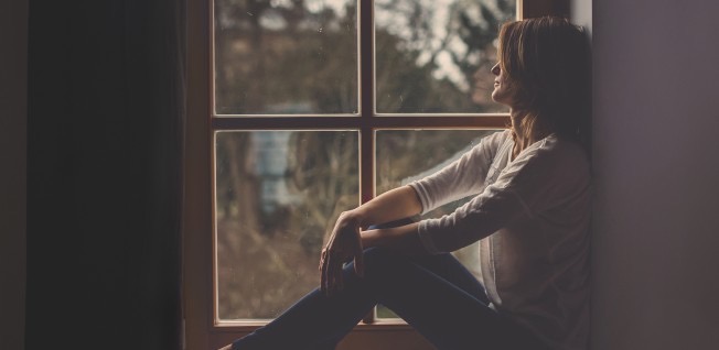 A woman sits by the window and is sad