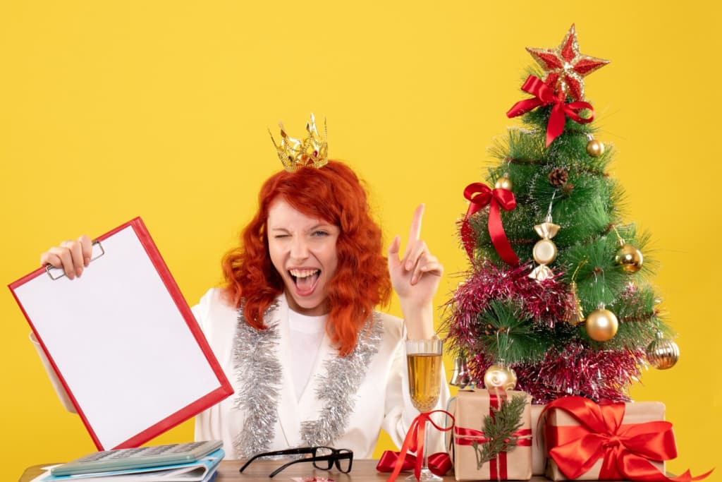 Front view of woman holding note around Christmas tree and gifts