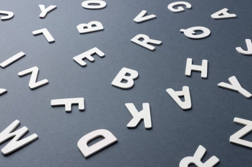 White alphabet letters scattered on a dark gray background
