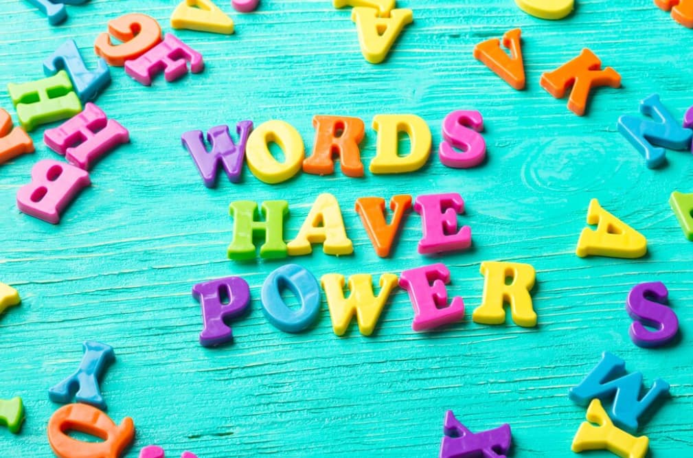 Colorful magnetic letters on a teal board spell "WORDS HAVE POWER"