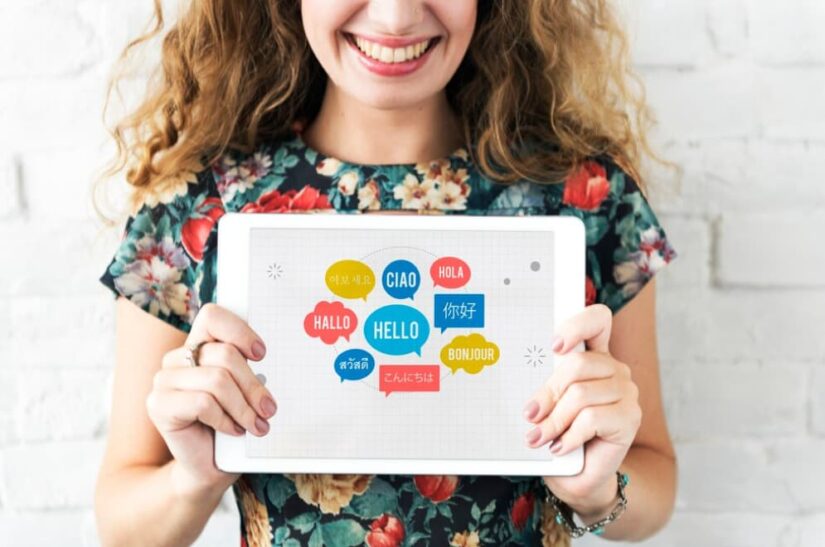 A woman holding a tablet displaying greetings in various languages