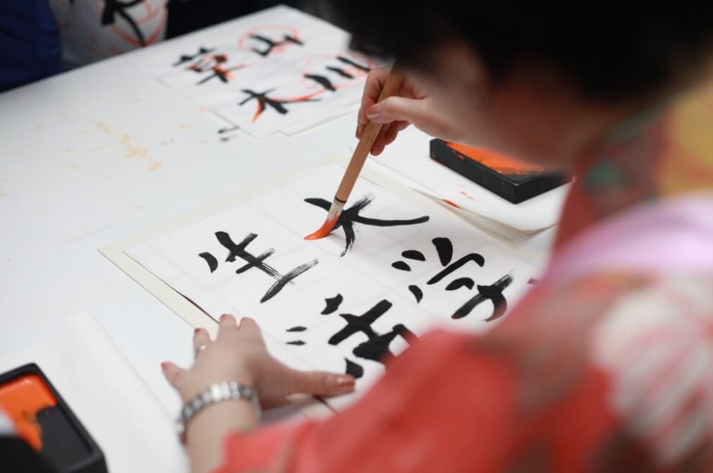 Someone practicing calligraphy with a thick brush on white paper